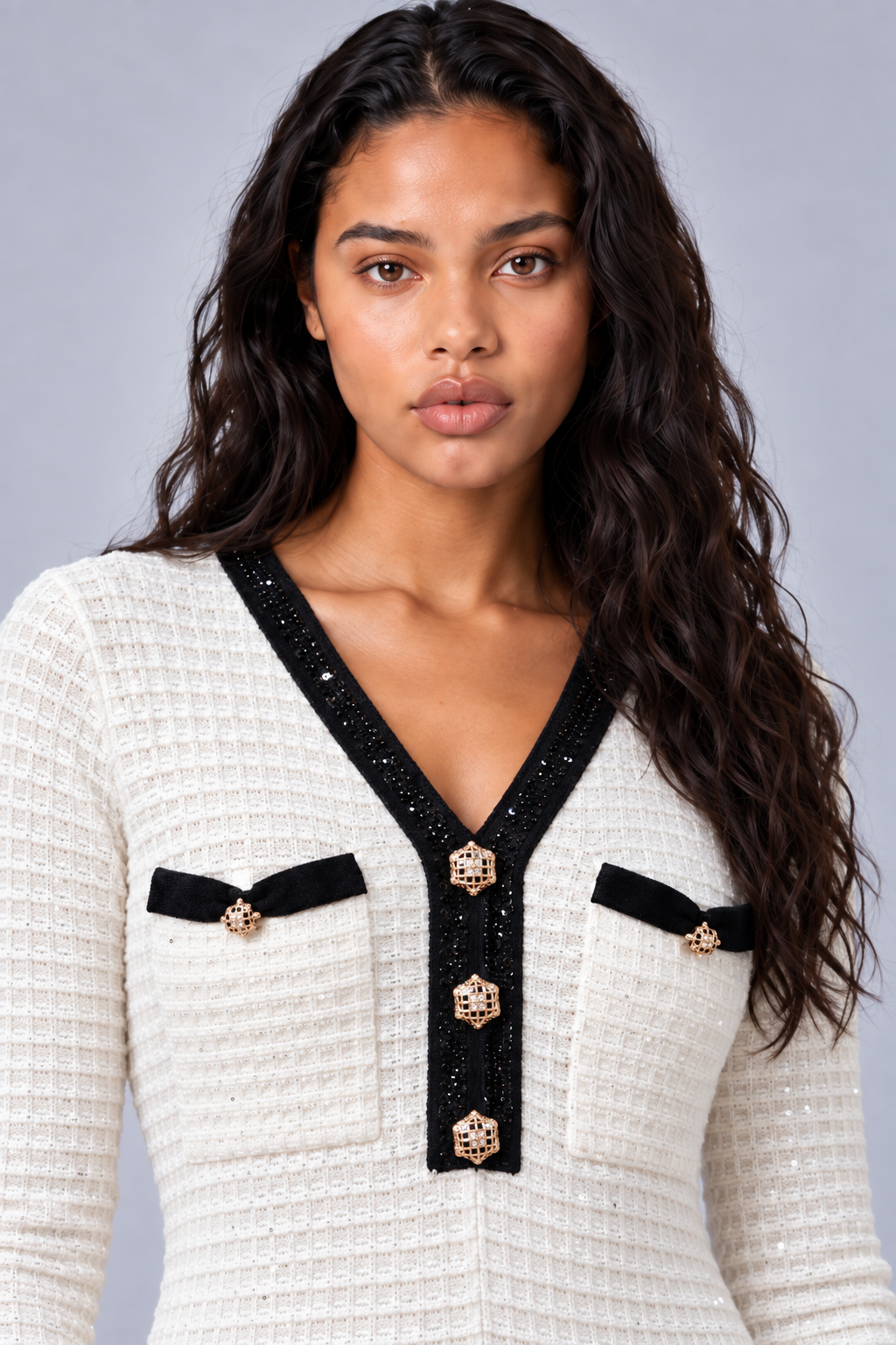 Front close-up of a model wearing the white Tally Taylor Textured Knit Dress - 51000 with black sequin trim, gold jeweled buttons, and black-trimmed chest pockets