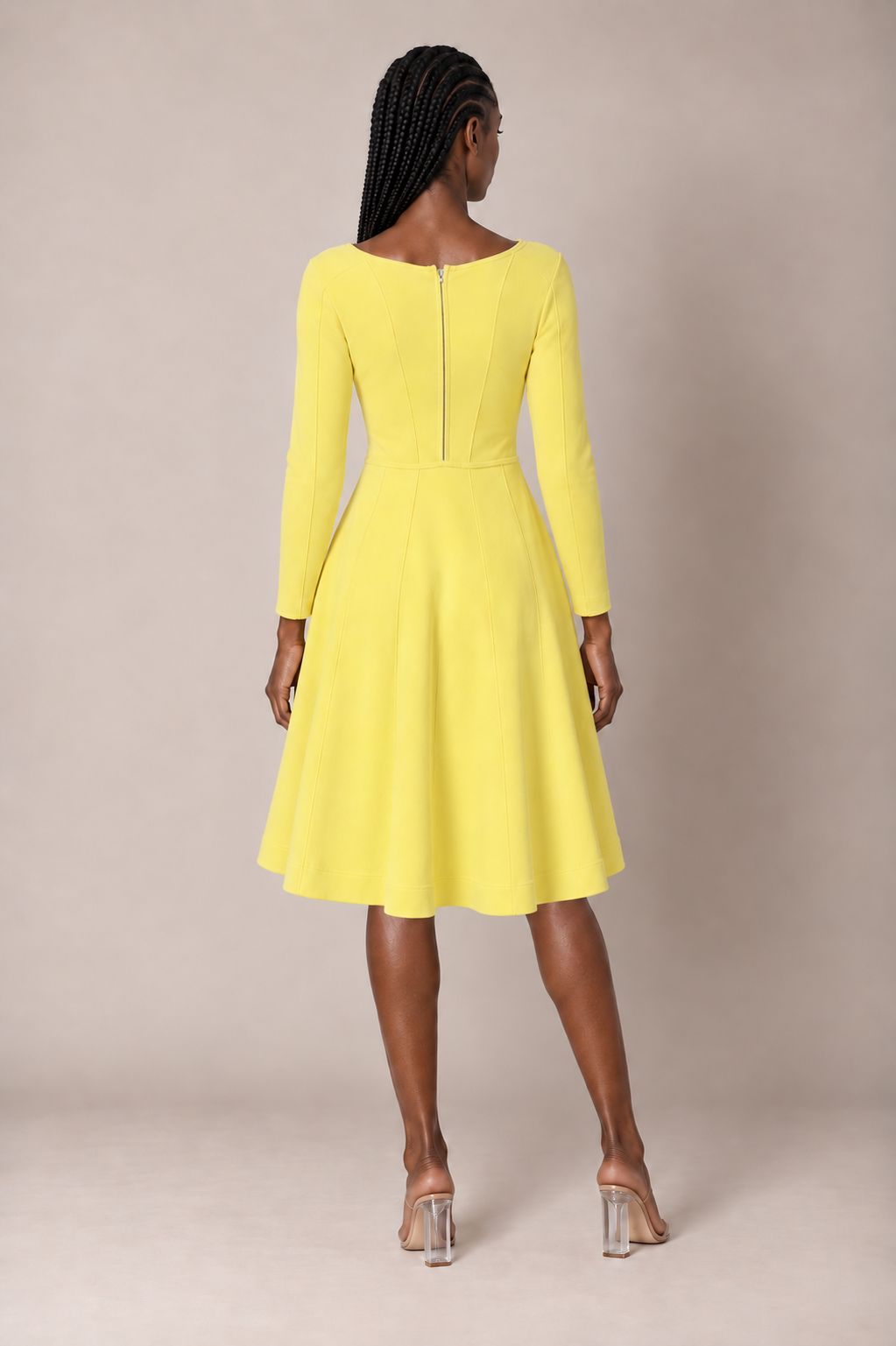 Back view of a model wearing the yellow Tally Taylor V-Neck Knit Dress with Gold Button Details - 51001, featuring long sleeves, paneled seams, a back zipper, and a flared knee-length skirt.