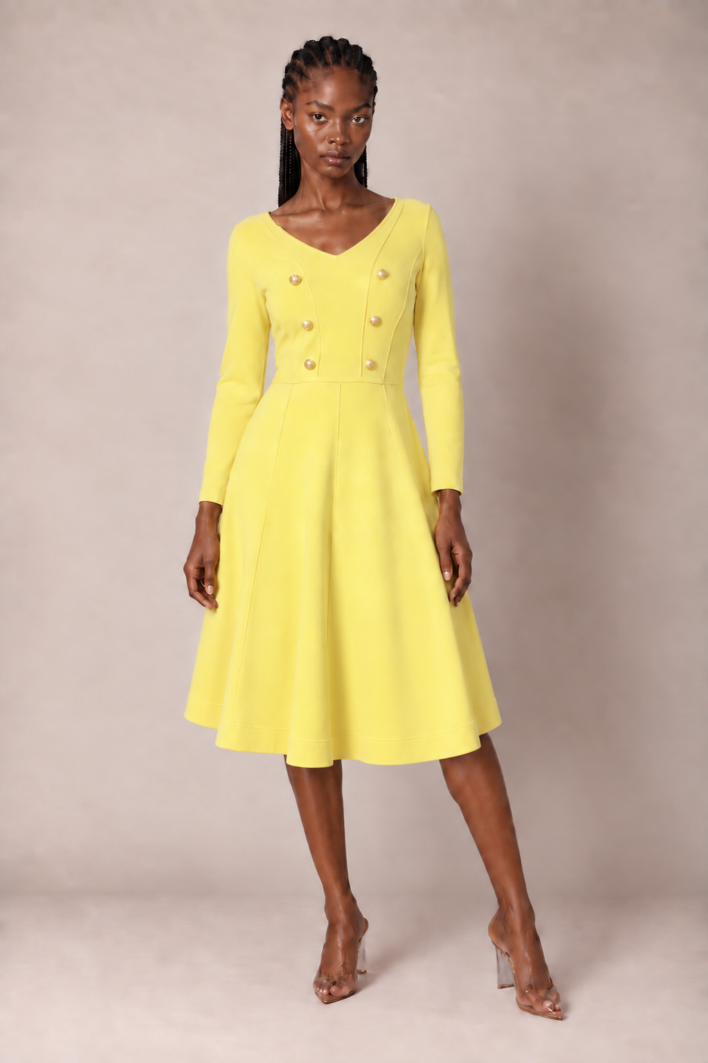 Front view of a model wearing the yellow Tally Taylor V-Neck Knit Dress with Gold Button Details - 51001, featuring long sleeves, a paneled bodice, double rows of gold buttons, and a flared knee-length skirt.