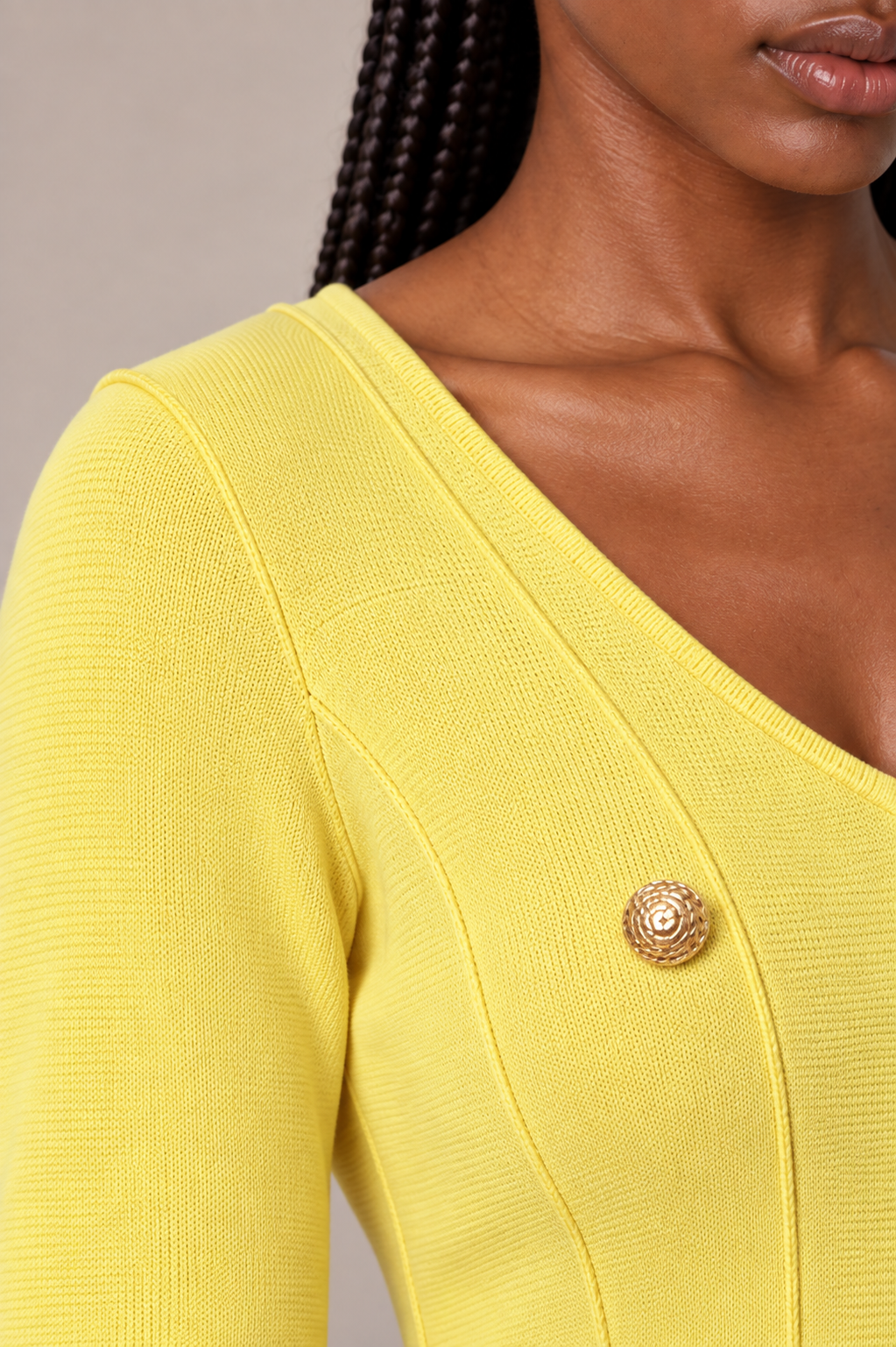 Shoulder close-up of a model wearing the yellow Tally Taylor V-Neck Knit Dress with Gold Button Details - 51001, highlighting the knit texture, V-neck edge, paneled seam, and gold button detail.