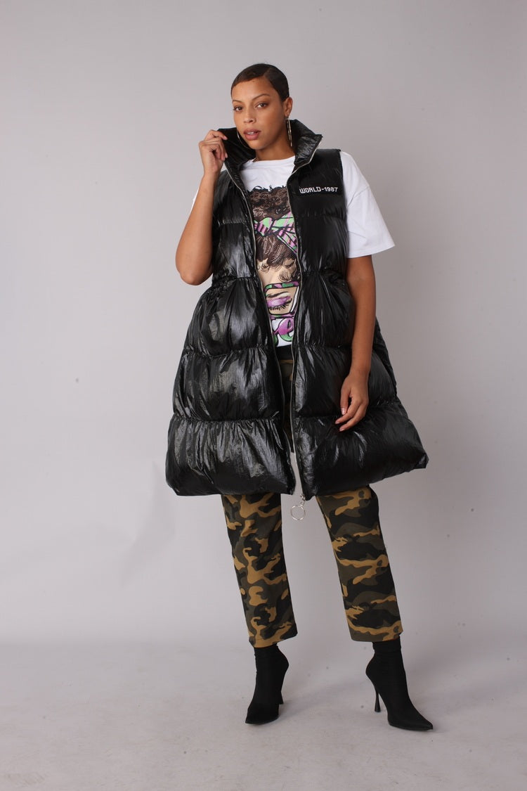 Three-quarter side view of black tiered puffer vest — For Her NYC.