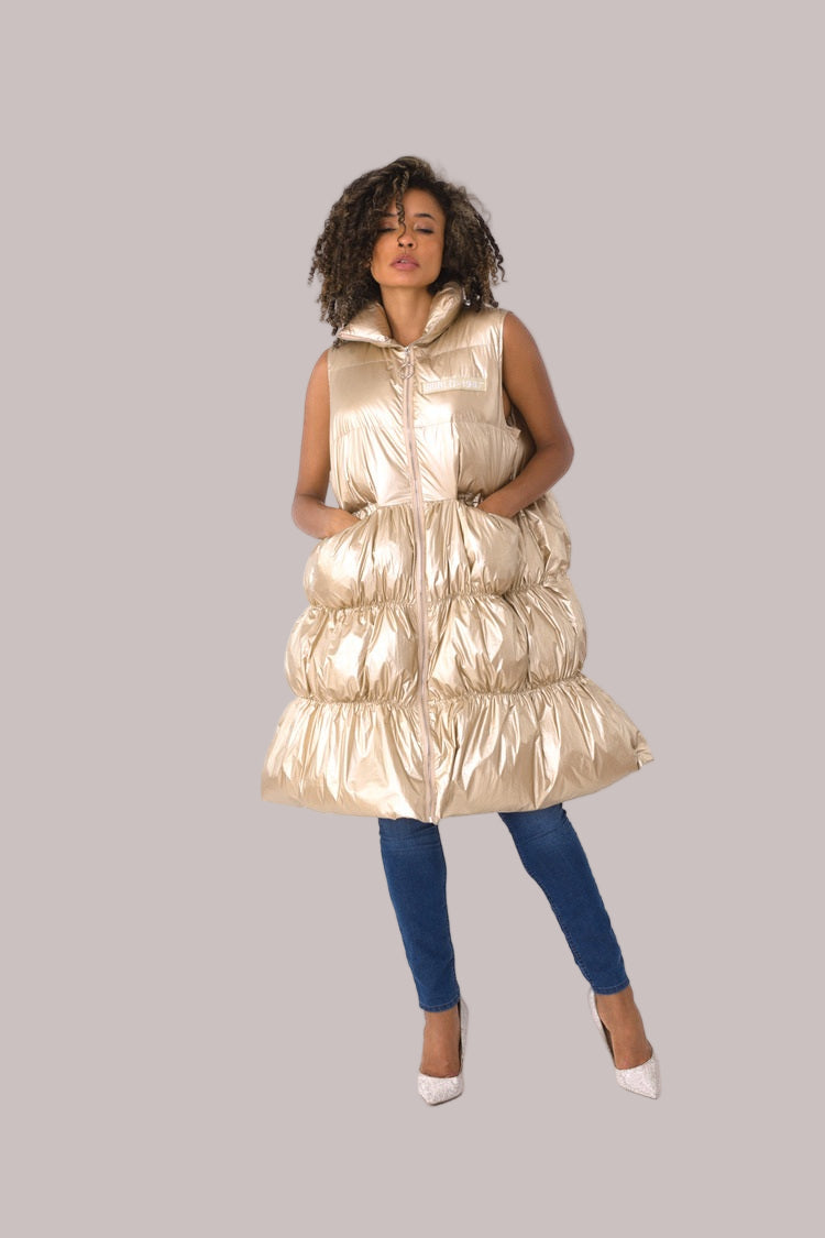 Front view of gold tiered puffer vest with exaggerated volume and zip-up closure — For Her NYC.