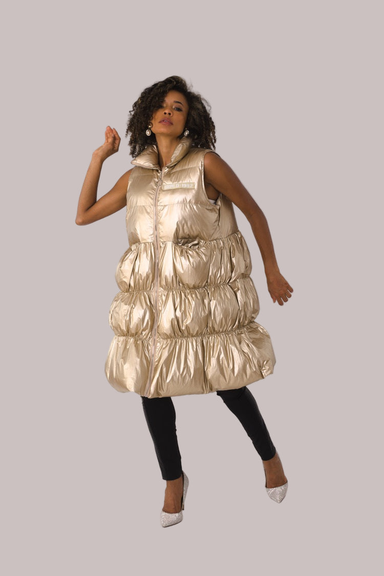 Front view of nude tiered puffer vest with shiny finish and high collar — For Her NYC.