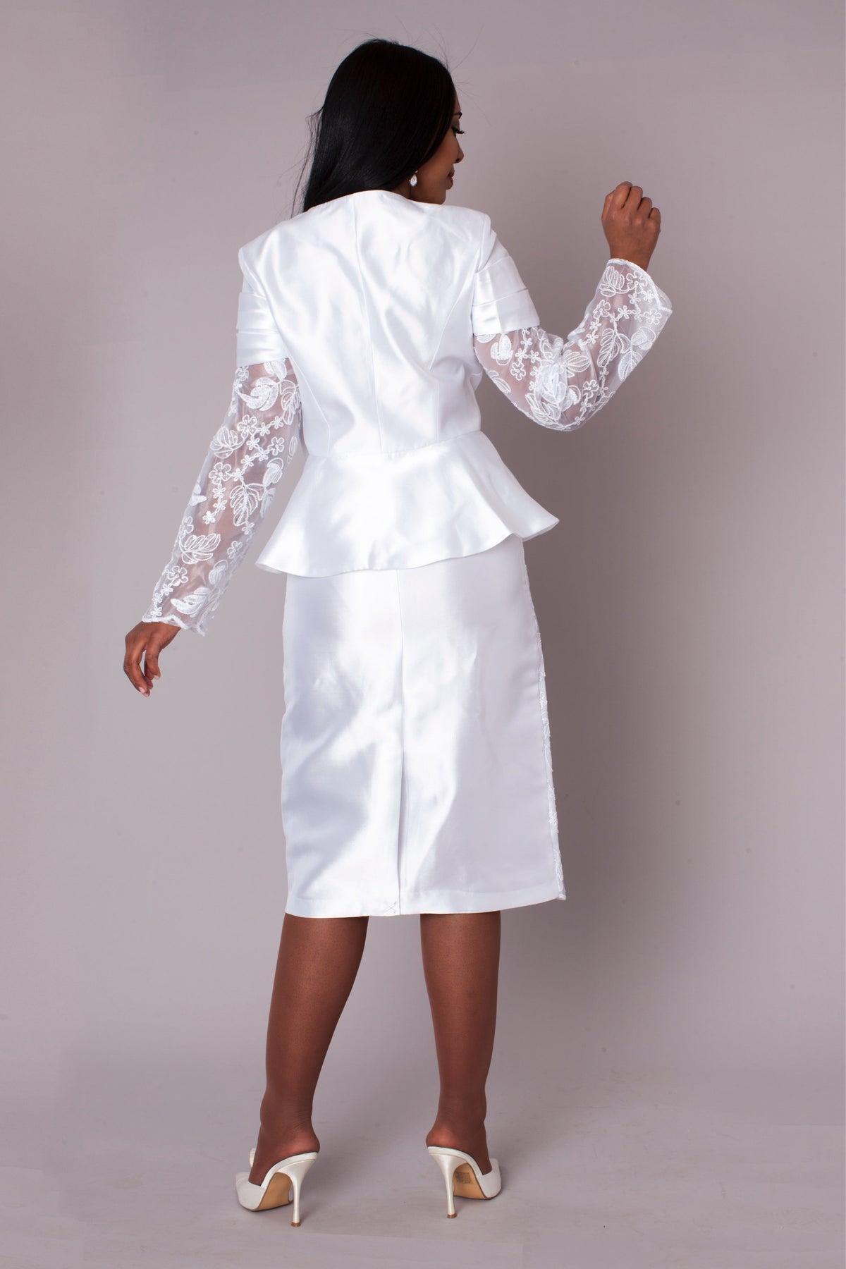 Model wearing white peplum church dress with lace sleeves, back standing pose by Tally Taylor