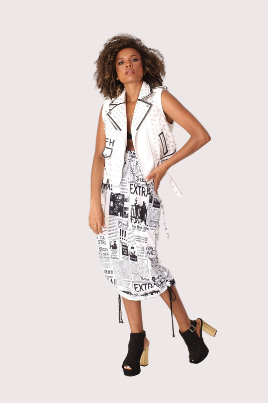Model wearing a newsprint woven midi skirt in a front walking pose, showcasing the ruched waist and slim midi silhouette, For Her NYC